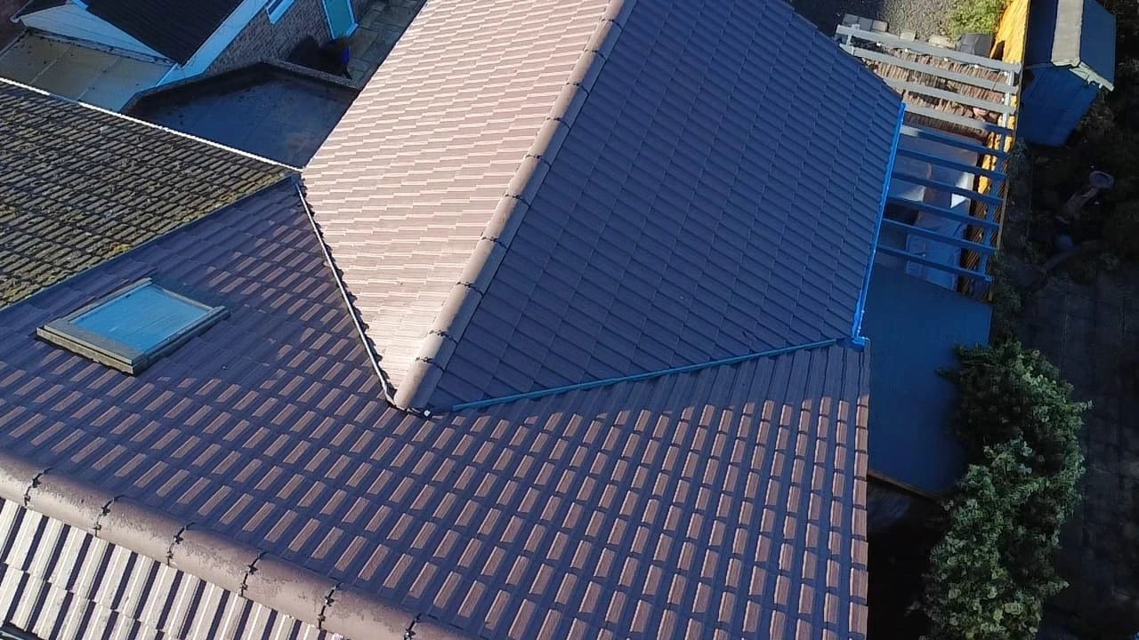 Aerial view of a roof with two textured sections, featuring a skylight and adjacent wooden structure.